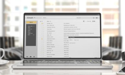 Image of a laptop screen showing a full email inbox with multiple subject lines and emails.