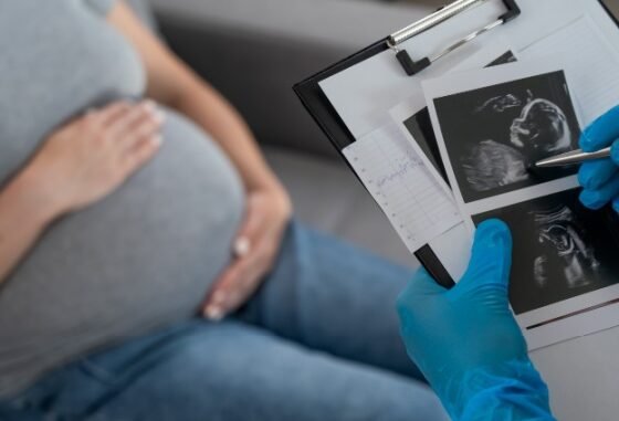 doctor holding ultrasound with pregnant woman