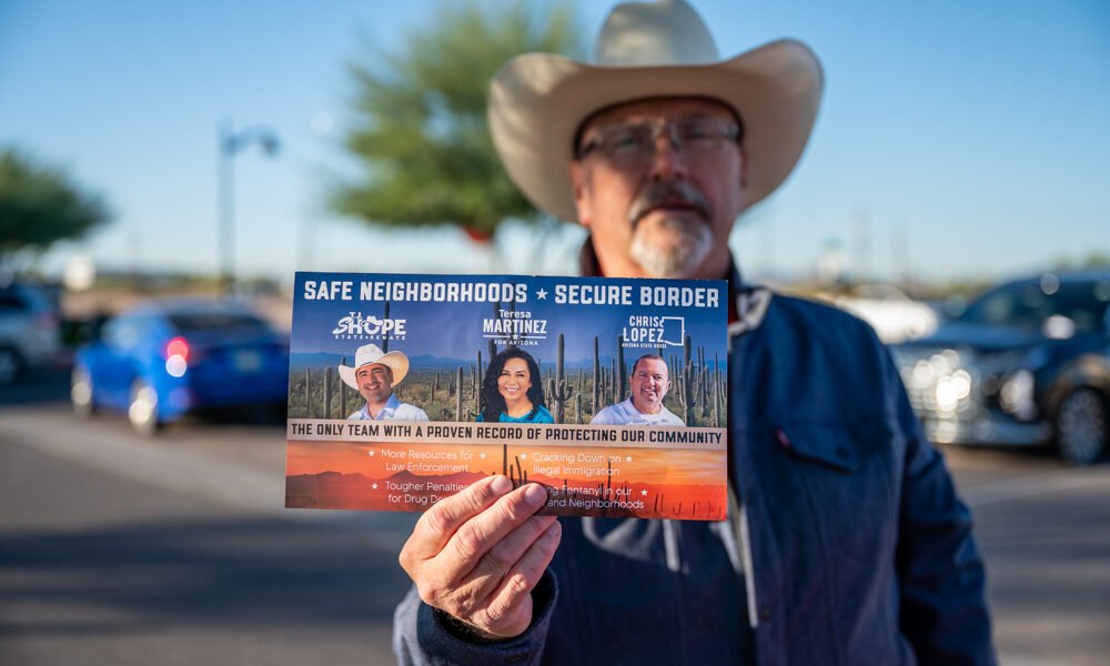 Andy Opary holds a card supporting T.J. Shope, Teresa Martinez and Chris Lopez outside a polling station in Maricopa on Nov. 5, 2024. [Bryan Mordt]