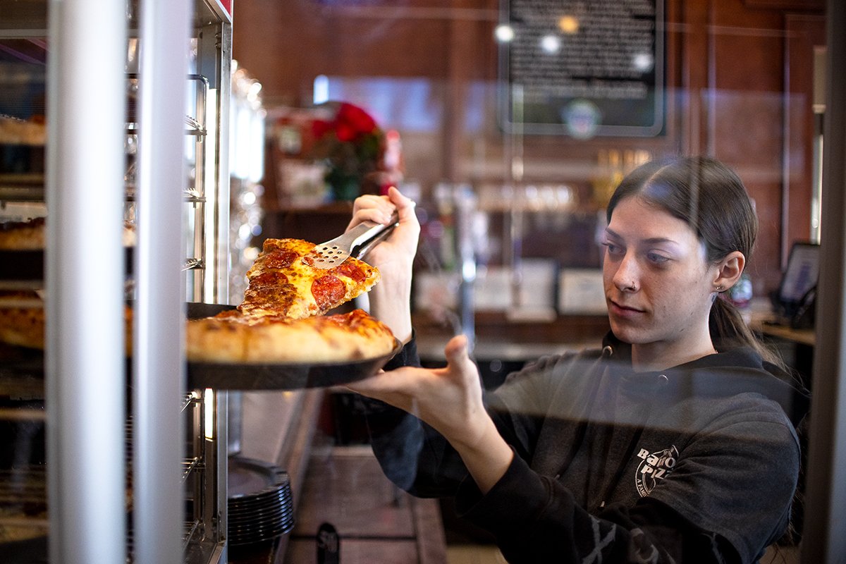 Barro's Pizza employee Madison Cross dishes a slice of pizza for the lunch crowd at the pizzeria on 44600 W. Smith Enke Road on Dec. 27, 2024. [Monica D. Spencer]