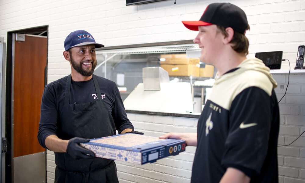 Vero Chicago Pizza Kitchen Manager Daniel Mejia hands a fresh pizza to employee Jonathan Jorgensen during the pizzeria's soft opening on June 6, 2024. [Monica D. Spencer]