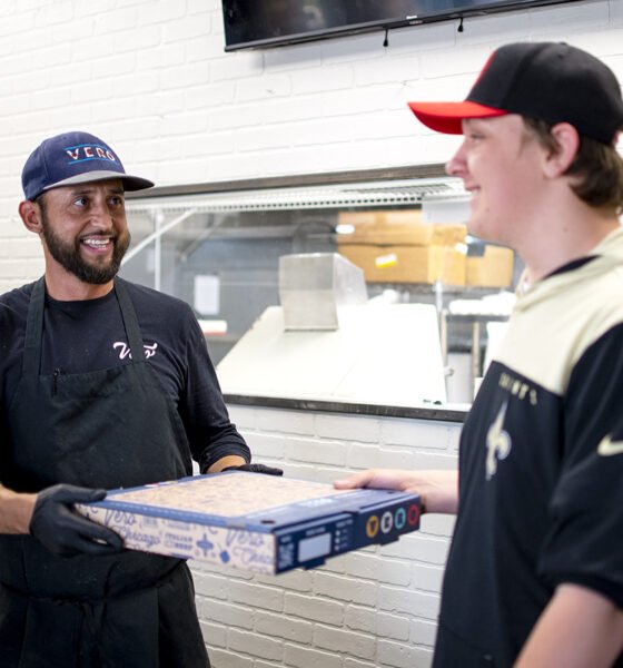 Vero Chicago Pizza Kitchen Manager Daniel Mejia hands a fresh pizza to employee Jonathan Jorgensen during the pizzeria's soft opening on June 6, 2024. [Monica D. Spencer]