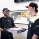 Vero Chicago Pizza Kitchen Manager Daniel Mejia hands a fresh pizza to employee Jonathan Jorgensen during the pizzeria's soft opening on June 6, 2024. [Monica D. Spencer]