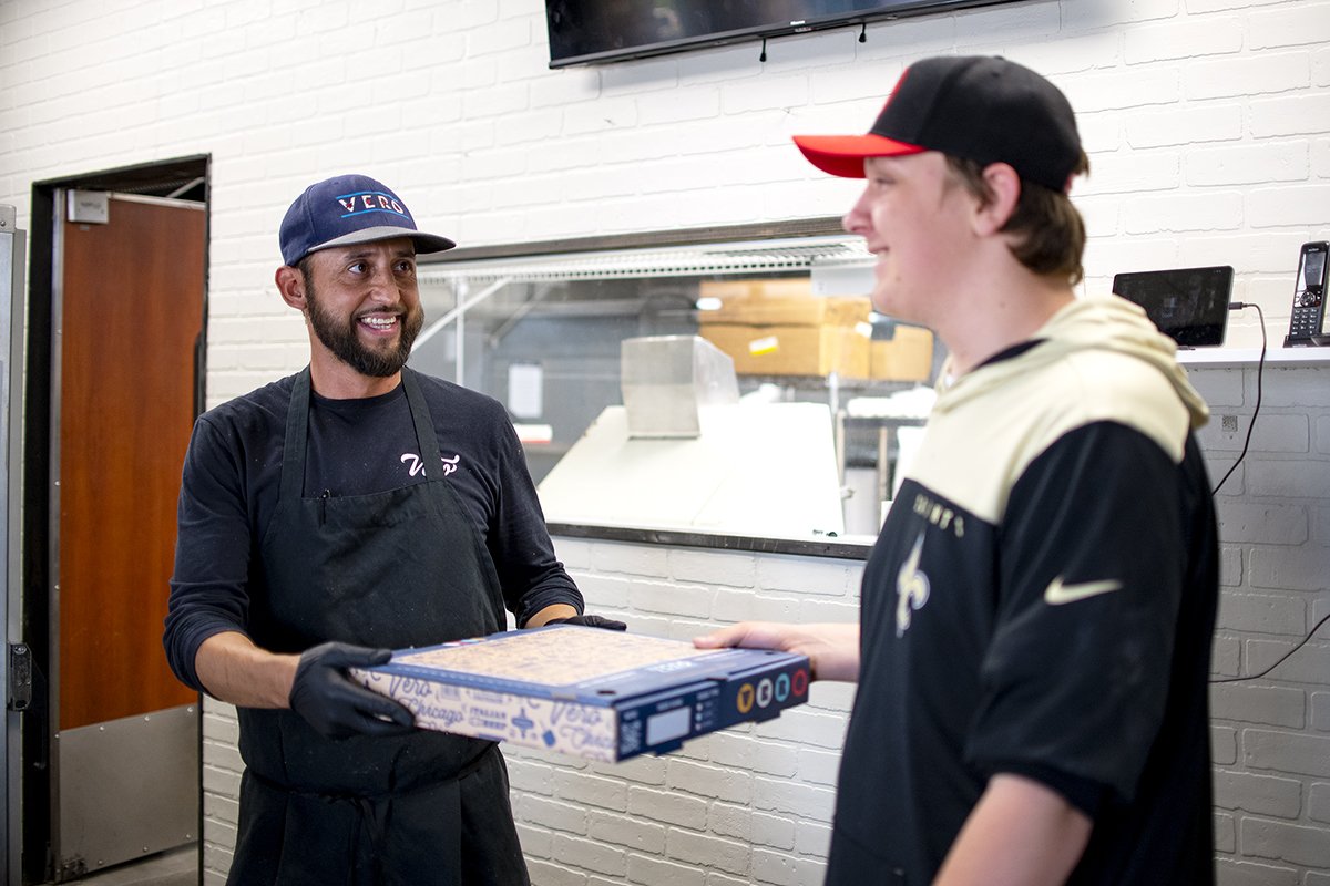 Vero Chicago Pizza Kitchen Manager Daniel Mejia hands a fresh pizza to employee Jonathan Jorgensen during the pizzeria's soft opening on June 6, 2024. [Monica D. Spencer]