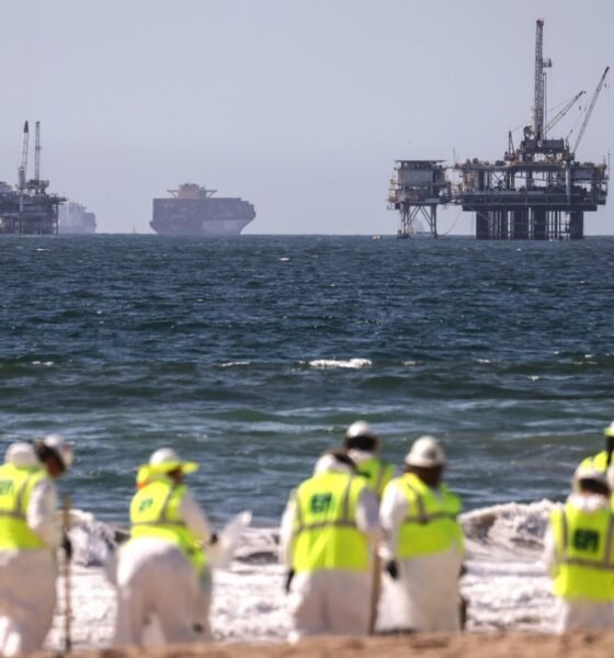 Cleanup workers search for contaminated sand and seaweed in front of drilling platforms and container ships about one week after an oil spill from an offshore oil platform on Oct. 9, 2021, in Huntington Beach, California. (Photo by Mario Tama/Getty Images)