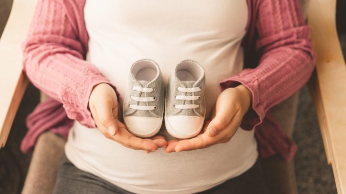 pregnant mother holding baby shoes