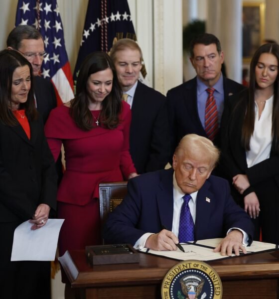 Surrounded by members of Congress and the family of Laken Riley, President Donald Trump signs the Laken Riley Act, the first piece of legislation passed during his second term in office, in the East Room of the White House on Jan. 29, 2025, in Washington, D.C.  U.S. Rep. Mike Collins, a Georgia Republican who represents the district where Riley was killed, is at far left.  (Photo by Chip Somodevilla/Getty Images)