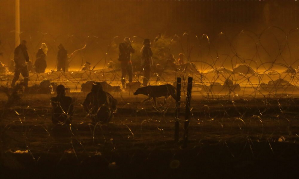 Migrants wait throughout the night May 10, 2023, in a dust storm at Gate 42, on land between the Rio Grande and the border wall. (Photo by Corrie Boudreaux for Source New Mexico)