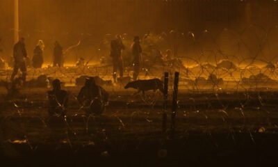 Migrants wait throughout the night May 10, 2023, in a dust storm at Gate 42, on land between the Rio Grande and the border wall. (Photo by Corrie Boudreaux for Source New Mexico)