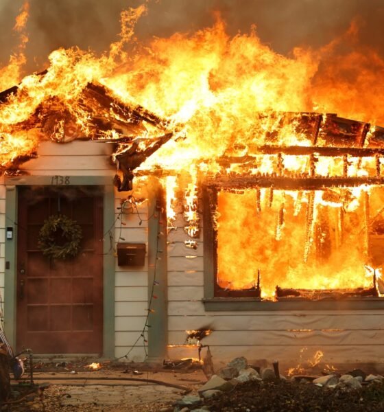 A person uses a garden hose in an effort to save a neighboring home from catching fire during the Eaton Fire on Jan. 8, 2025, in Altadena, California.  (Photo by Mario Tama/Getty Images)