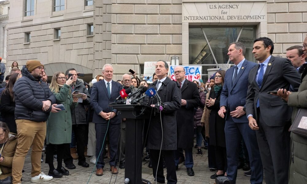 Sen. Chris Van Hollen, left, D-Md., and Rep. Jamie Raskin, D-Md., right, speak to a crowd gathered at the shuttered Washington, D.C., headquarters of the U.S. Agency for International Development on Feb. 3, 2025. (Photo by Ashley Murray/States Newsroom)