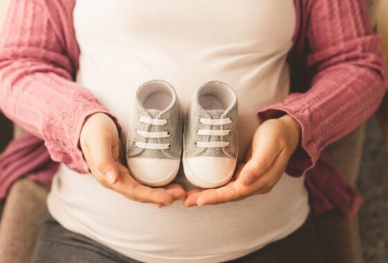 pregnant mother holding baby shoes