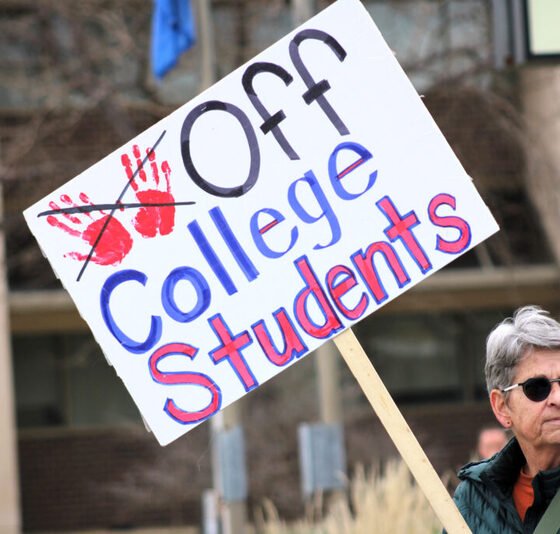 Protestor Pat Braun carries a sign April 23, 2025, in Rapid City, South Dakota, to protest the cancellation of student visas. (Photo by Seth Tupper/South Dakota Searchlight) 