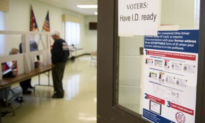 A voter shows identification to an election judge. (Photo by Jeff Swensen/Getty Images)