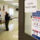 A voter shows identification to an election judge. (Photo by Jeff Swensen/Getty Images)