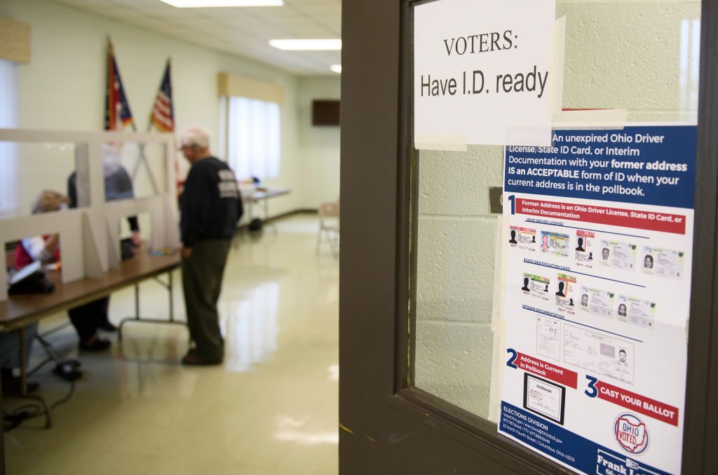 A voter shows identification to an election judge. (Photo by Jeff Swensen/Getty Images)
