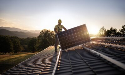 A worker installs a solar panel on a roof. (Getty Images)