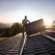 A worker installs a solar panel on a roof. (Getty Images)