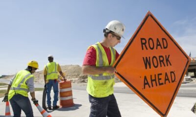 Workers moving equipment and road signs on a highway. (Getty Images)  