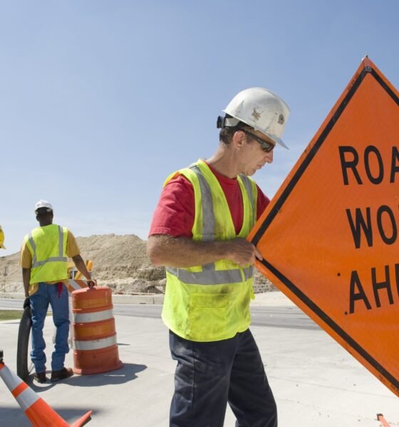 Workers moving equipment and road signs on a highway. (Getty Images)  